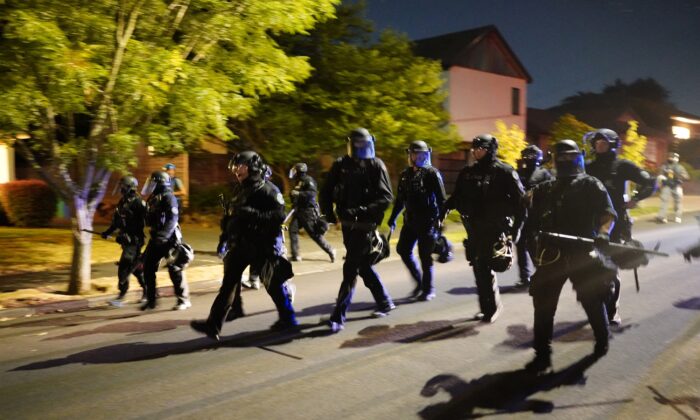 Portland police officers pursue a crowd of about 200 after forcing the group to disperse from a law enforcement precinct in Portland, Ore., late Aug. 1, 2020. (Nathan Howard/Getty Images)