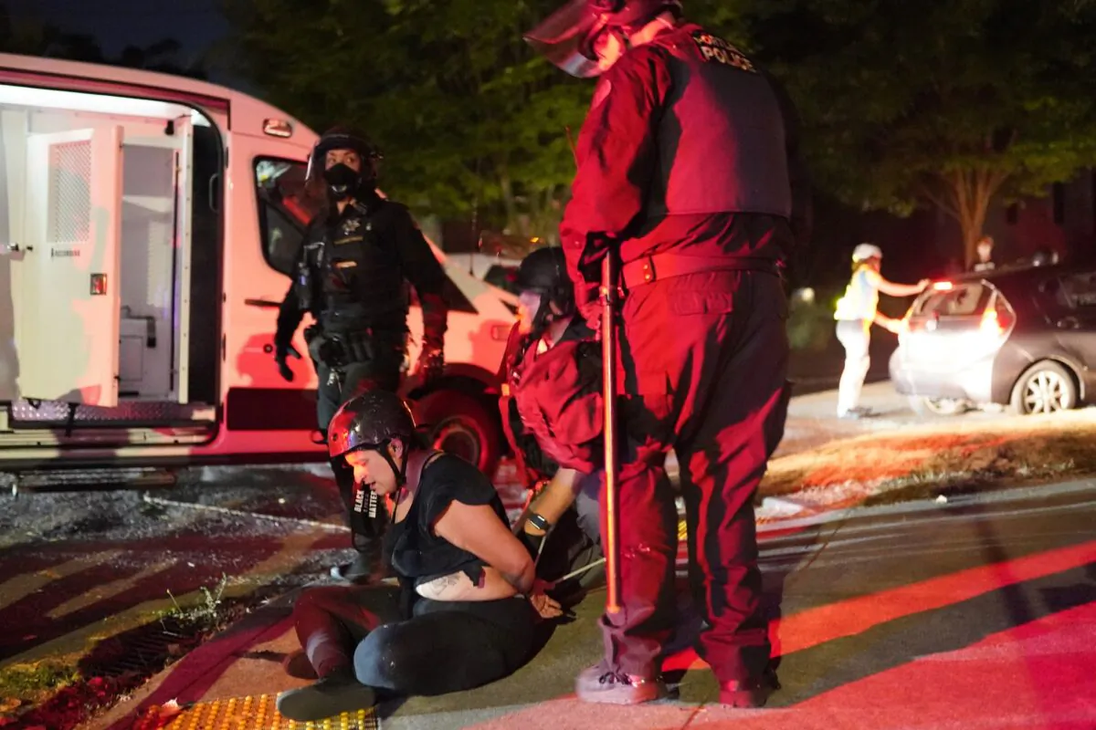 Portland police officers arrest a protester after dispersing a crowd of about 200 people from in front of a precinct for the Portland Police Bureau and Multonomah County Sheriff's Office in Portland, Ore., on Aug. 1, 2020. (Nathan Howard/Getty Images)