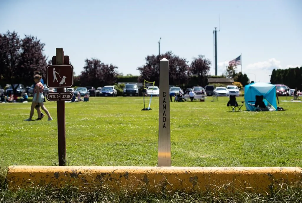 A Canada-U.S. border marker is seen in Surrey, B.C., as people gather at Peace Arch Historical State Park in Blaine, Wash., on July 5, 2020. (Darryl Dyck/The Canadian Press)