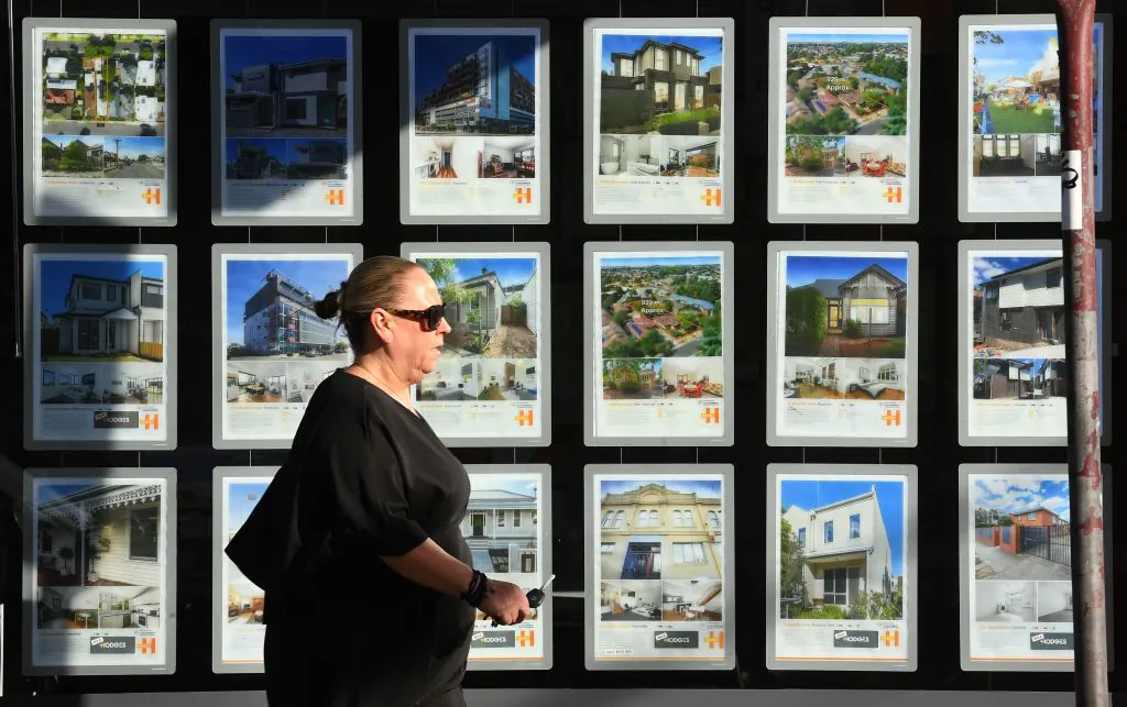 A woman walks past a real estate agent's window advertising houses for sale and auction in Melbourne, Australia on May 1, 2019. (William West/Getty Images)