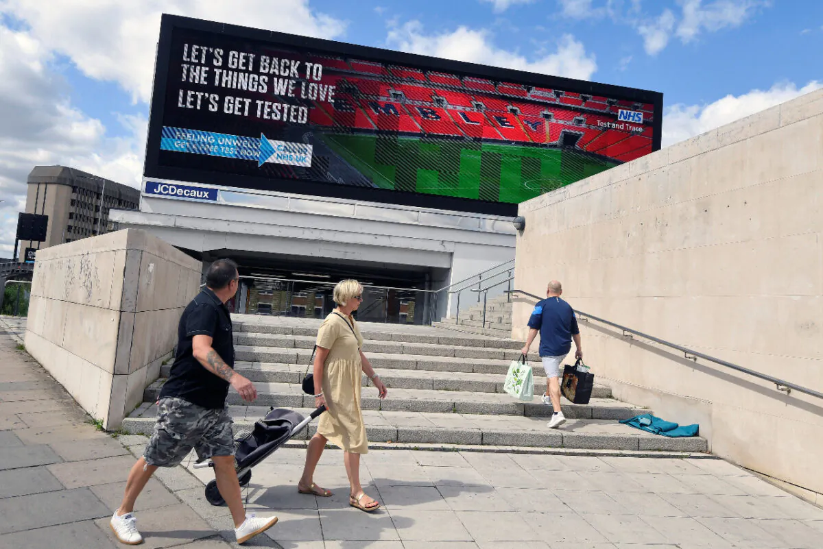 People walk past a British government public health campaign advertisement encouraging people to get tested, amid the spread of the CCP virus in London, Britain on Aug. 2, 2020. (Reuters/Toby Melville)