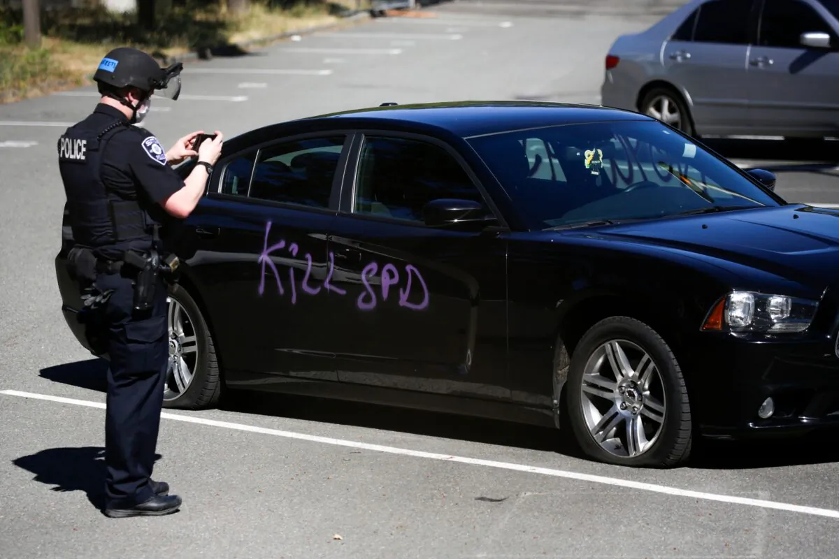 A Seattle police officer photographs graffiti that says "kill SPD" at the King County Juvenile Detention Center in Seattle, Wash., on July 25, 2020. (Jason Redmond/AFP via Getty Images)
