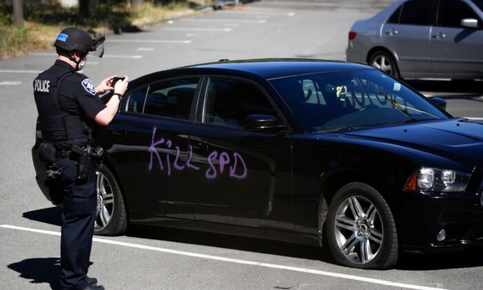 A Seattle police officer photographs graffiti that says "kill SPD" at the King County Juvenile Detention Center in Seattle, Wash., on July 25, 2020. (Jason Redmond/AFP via Getty Images)