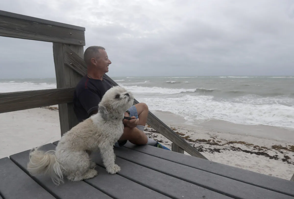 Kent Ahern and his dog Blanco watch waves churned up by Tropical Storm Isaias near Jaycee Beach Park, in Vero Beach, Fla., on Aug. 2, 2020. (Wilfredo Lee/AP Photo)