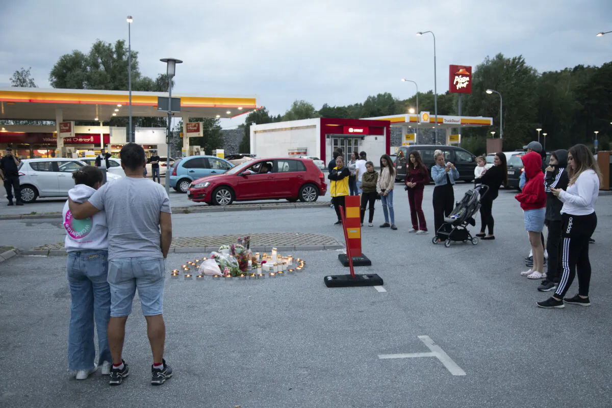 Flowers and candles are placed near where a twelve-year-old girl was shot and killed near a petrol station in Botkyrka, south of Stockholm, Sweden, Aug. 2, 2020. (Ali Lorestani//TT via AP Photo)