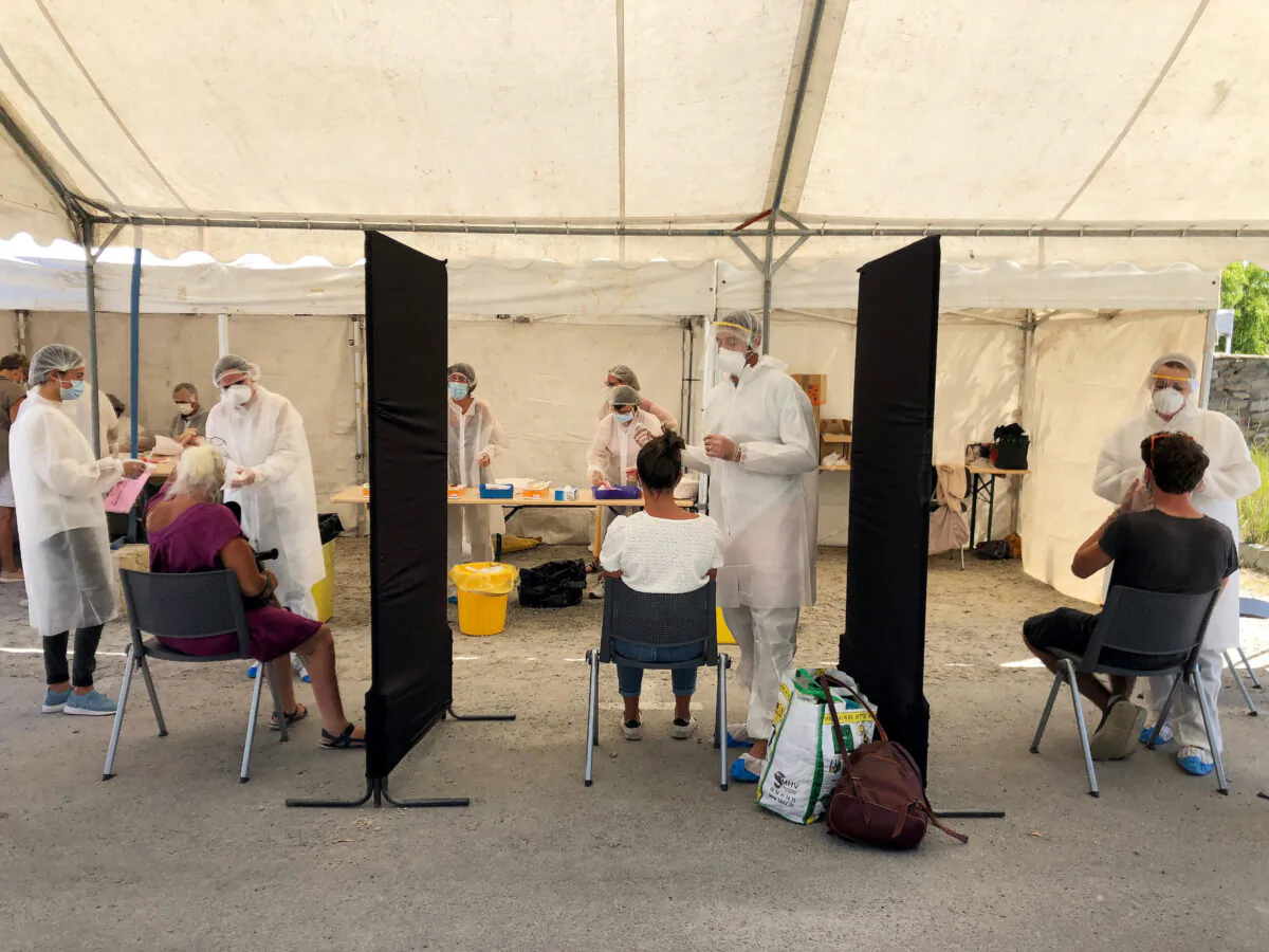 Healthcare workers collect samples in a walk-through test site to detect possible coronavirus infections after the emergence of a cluster of cases due to the illegal opening of the Hacienda Cafe nightclub in Quiberon, France, on July 29, 2020. (Caroline Paillez/Reuters)