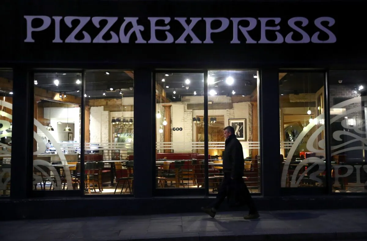A person is seen walking past an empty Pizza Express restaurant in London, Britain, on March 17, 2020. (Hannah McKay/Reuters)