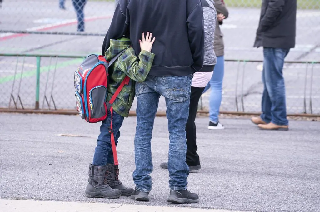 A boy hugs his father as he waits to be called to enter the schoolyard the Marie-Derome School in Saint-Jean-sur-Richelieu, Que. on May 11, 2020. Plans are being made across the country for how to safely send students back to school in the fall as the COVID-19 pandemic continues. (Paul Chiasson/ The Canadian Press)