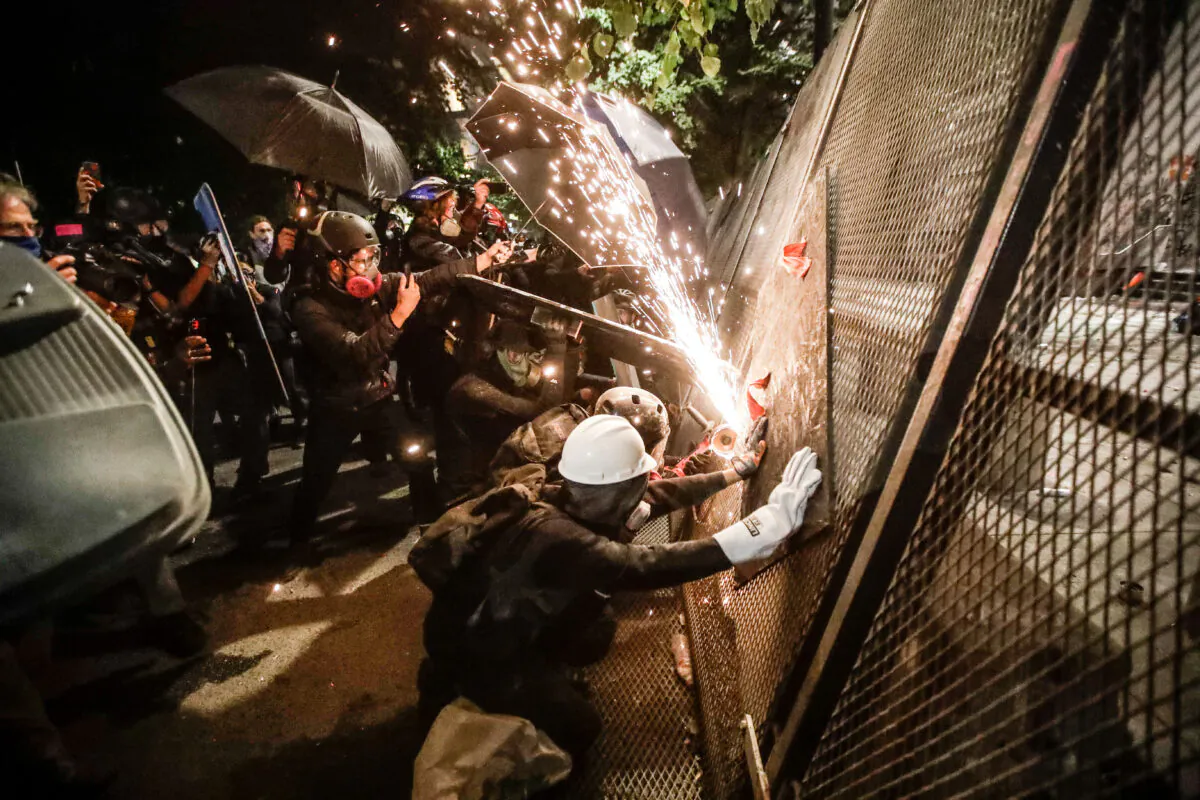 Rioters try to cut through a steel fence at the Mark O. Hatfield U.S. Courthouse in Portland, Ore., on July 24, 2020. (Marcio Jose Sanchez/AP Photo)