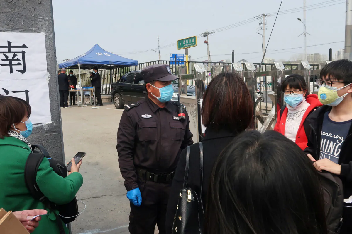 People wearing face masks to prevent the spread of the (COVID-19) wait at an entrance to a labor arbitration office in Beijing, China, on April 9, 2020. (Martin Pollard/Reuters)