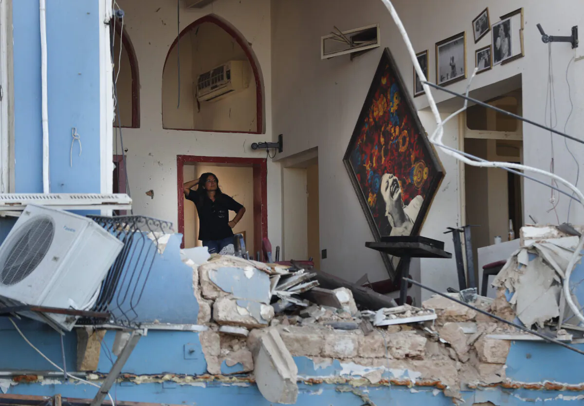 A woman stands inside a damaged restaurant a day after an explosion hit the seaport of Beirut, Lebanon on Aug. 5, 2020. (AP Photo/Hussein Malla)
