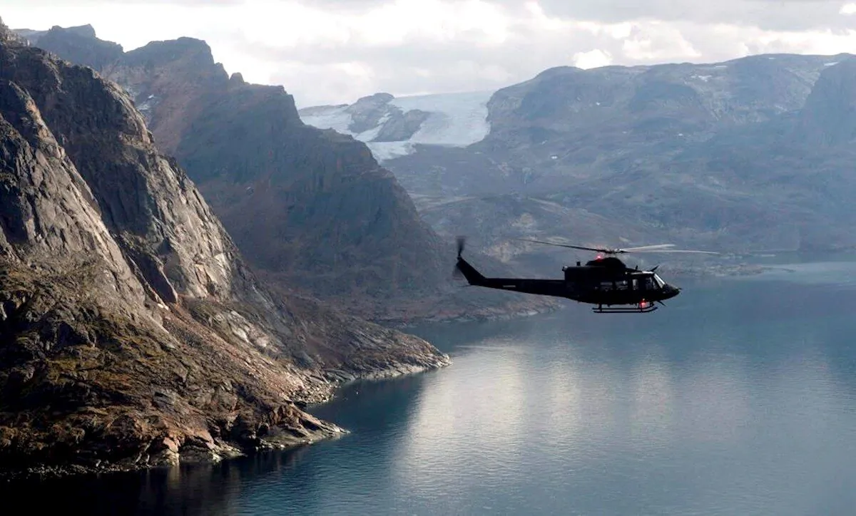 A Canadian military Griffon helicopter flies along the shoreline of Baffin Island as it moves personnel between Operation Nanook and Iqaluit, on Aug. 26, 2014. (Adrian Wyld/The Canadian Press)