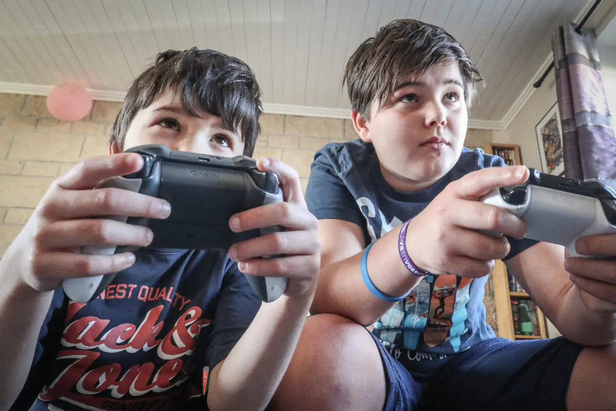 Two boys playing with an XBox game console in Vezin, Belgium, on March 26, 2020. (Bruno Fahy/Belga Mag/AFP via Getty Images)