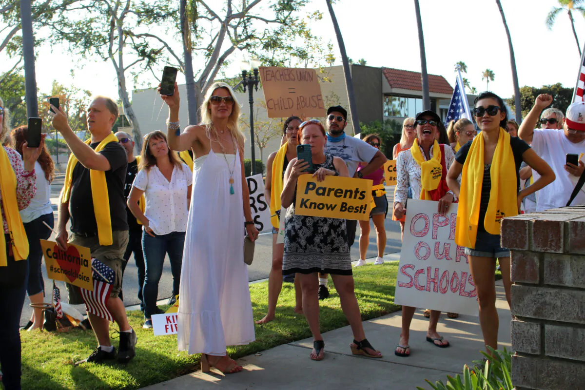 Parents hold signs and cell phones at a gathering to protest mandated school closures amid the COVID-19 pandemic in Santa Ana, Calif., on Aug. 4, 2020. (Jamie Joseph/The Epoch Times)
