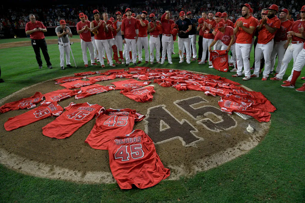 Los Angeles Angels public relations employee Eric Kay, left, joins the Angels players as they lay their jerseys on the pitcher's mound in honor of fallen teammate Tyler Skaggs after they won a combined no-hitter against the Seattle Mariners at Angel Stadium in Anaheim, Calif., on July 12, 2019. (John McCoy/Getty Images)