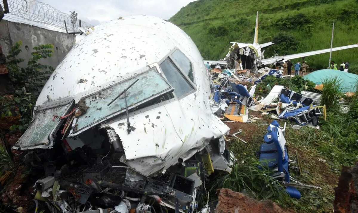 People stand by the debris of the Air India Express flight that skidded off a runway while landing in Kozhikode, Kerala state, India, Sat., Aug. 8, 2020. (Shijith Sreedhar/AP Photo)