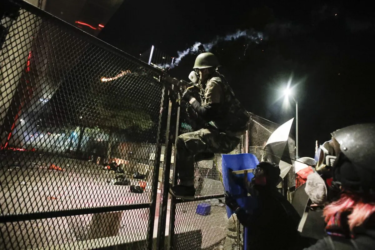 A rioter climbs over the fence outside the Mark O. Hatfield U.S. Courthouse in Portland, Ore., on July 26, 2020. (Marcio Jose Sanchez/AP Photo)