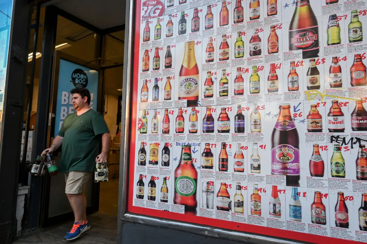 A man leaves a "bottle shop" displaying a sign showing dozens of beers for sale, in Melbourne, Australia on March 31, 2020. (William West/AFP via Getty Images)