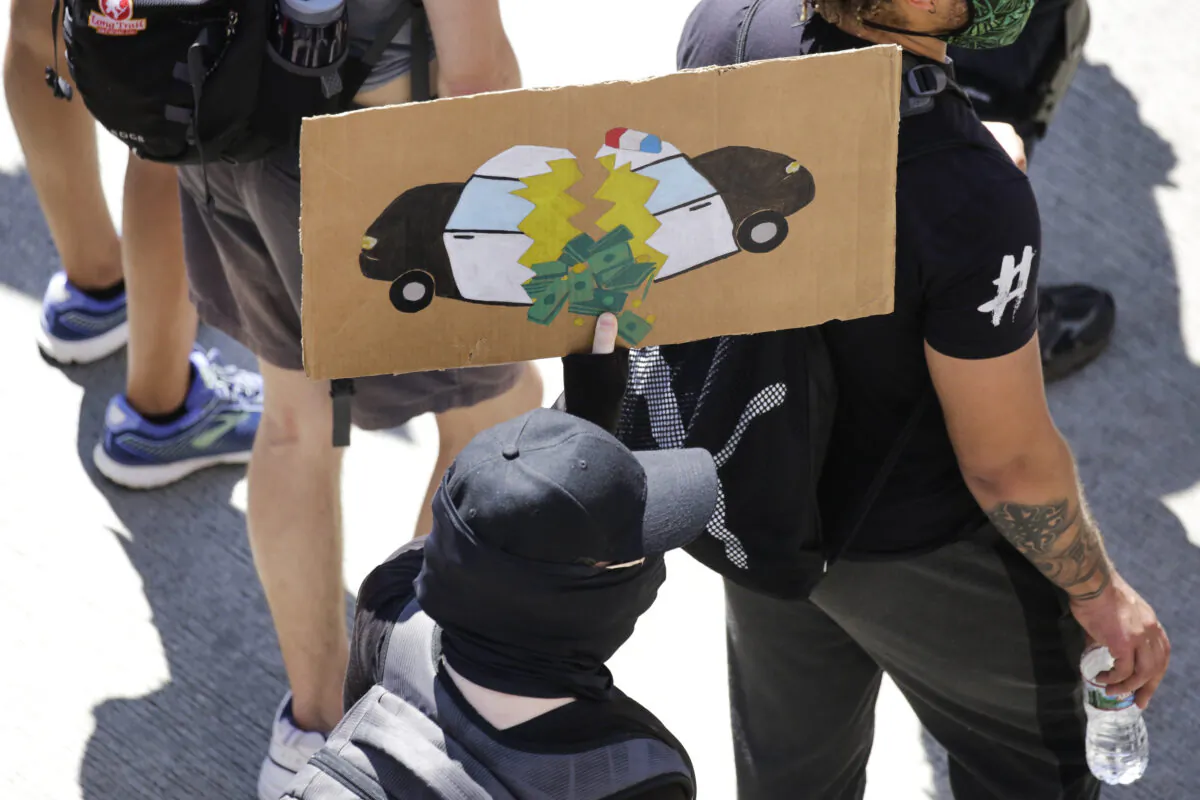 A protester carries a sign during a "Defund the Police" march from King County Youth Jail to City Hall in Seattle, Wash., on Aug. 5, 2020. (Jason Redmond/AFP via Getty Images)