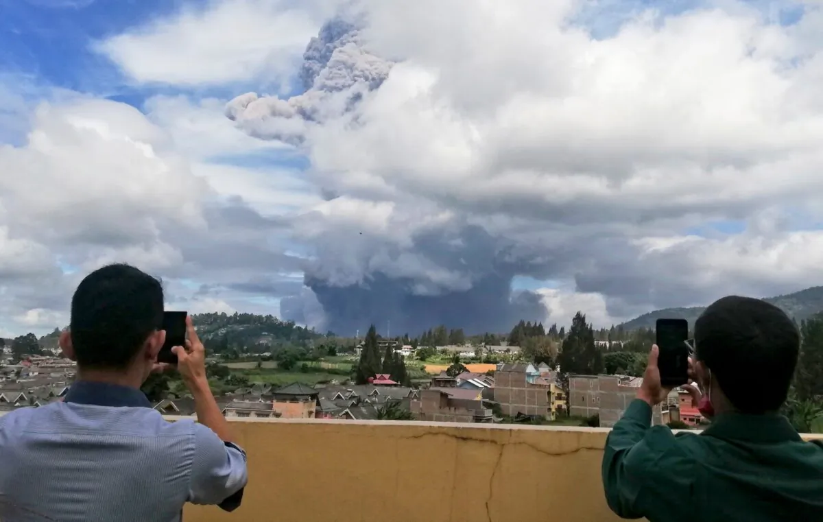 Indonesian men use their mobile phones to take photos as Mount Sinabung spews volcanic materials into the air as it erupts, in Karo, North Sumatra, Indonesia, on Aug. 10, 2020. (Sugeng Nuryono/AP Photo)