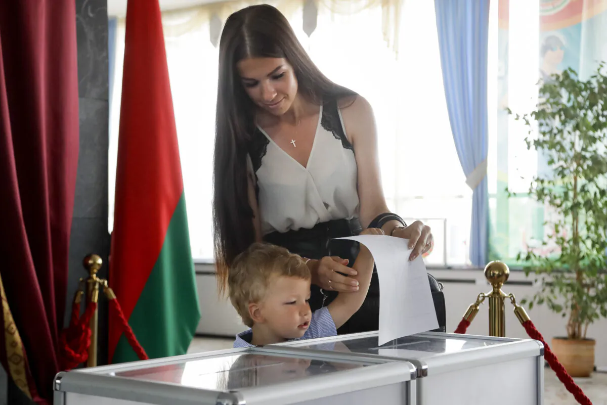 A child helps his mother cast her ballot at a polling station during the presidential election in Minsk, Belarus, on Aug. 9, 2020. (AP Photo/Sergei Grits)