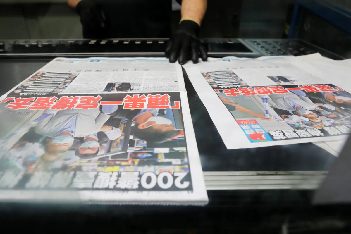 An employee checks the print quality of copies of the Apple Daily newspaper,  with a headline "Apple Daily will fight on" after media mogul Jimmy Lai Chee-ying was arrested by the national security unit, at the company's printing facility in Hong Kong on Aug. 11, 2020. (Tyrone Siu/Reuters)