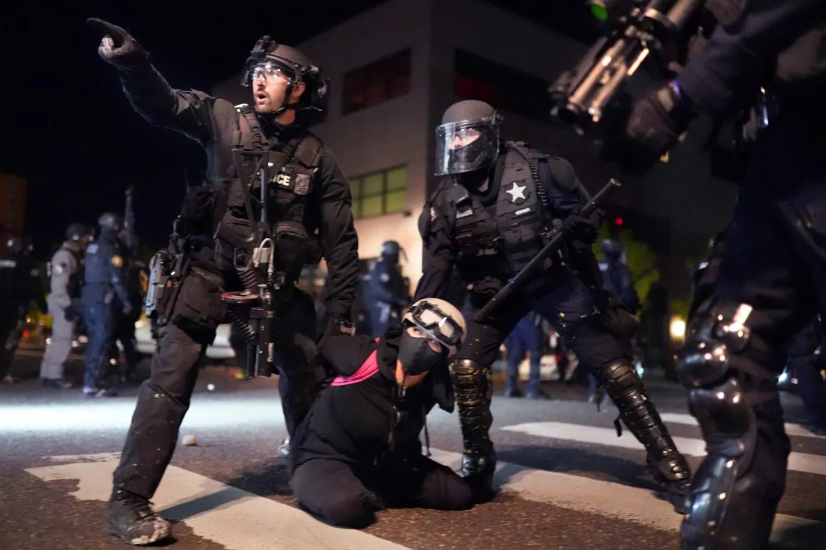 Portland Police and Oregon State Patrol officers work together to arrest a protester in front of the Portland Police Bureau North Precinct on the 75th day of protests and riots, in Portland, Ore., on Aug. 11, 2020. (Nathan Howard/Getty Images)