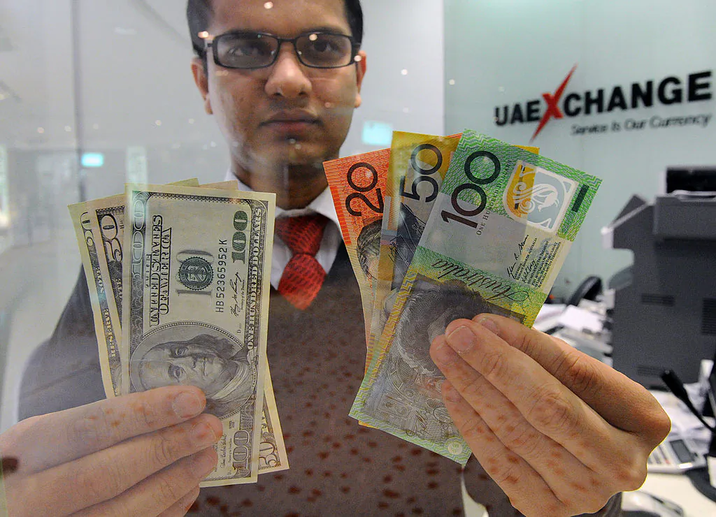 Money changer Tirth Acharya of India displays a selection of U.S. dollars (L) and Australian polymer notes (R) as the local currency reached parity in Sydney on May 14, 2012. (Torsten Blackwood/Getty Images)