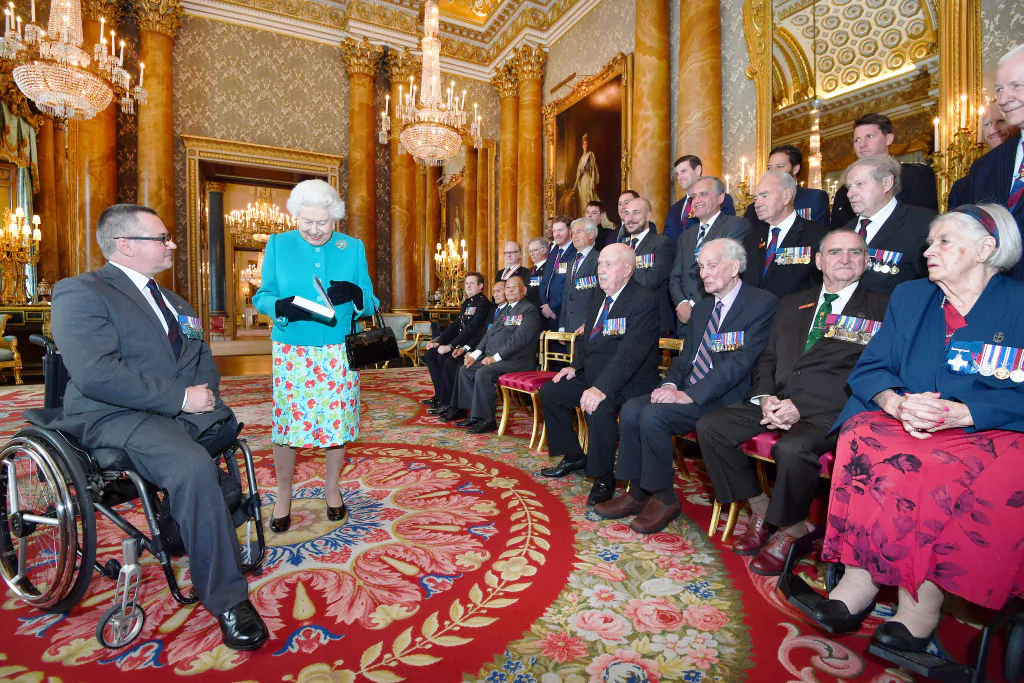 Queen Elizabeth II is given a book by Major Peter Norton GC, which recalls the exploits by the twenty-five living recipients of the Victoria and George Cross medals, during a reception for the Victoria Cross and George Cross Association at in the Picture Gallery at Buckingham Palace on May 16, 2018 in London, England. (John Stillwell - Pool/Getty Images)
