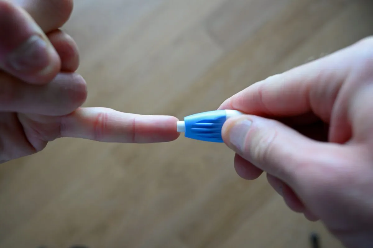 A man uses a lancet to prick the tip of his finger to provide blood for a CCP virus antibody test in London on May 28, 2020. (Justin Tallis/AFP via Getty Images)
