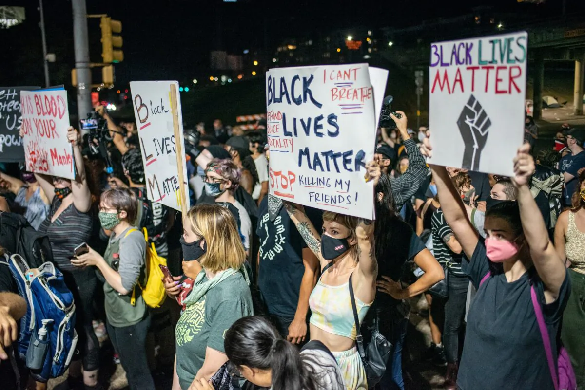 People hold up signs outside Austin Police Department after a vigil for Garrett Foster, a Black Lives Matter protester who was shot dead after allegedly brandishing his firearm at a driver, in Austin ,Texas, on July 26, 2020. (Sergio Flores/Getty Images)