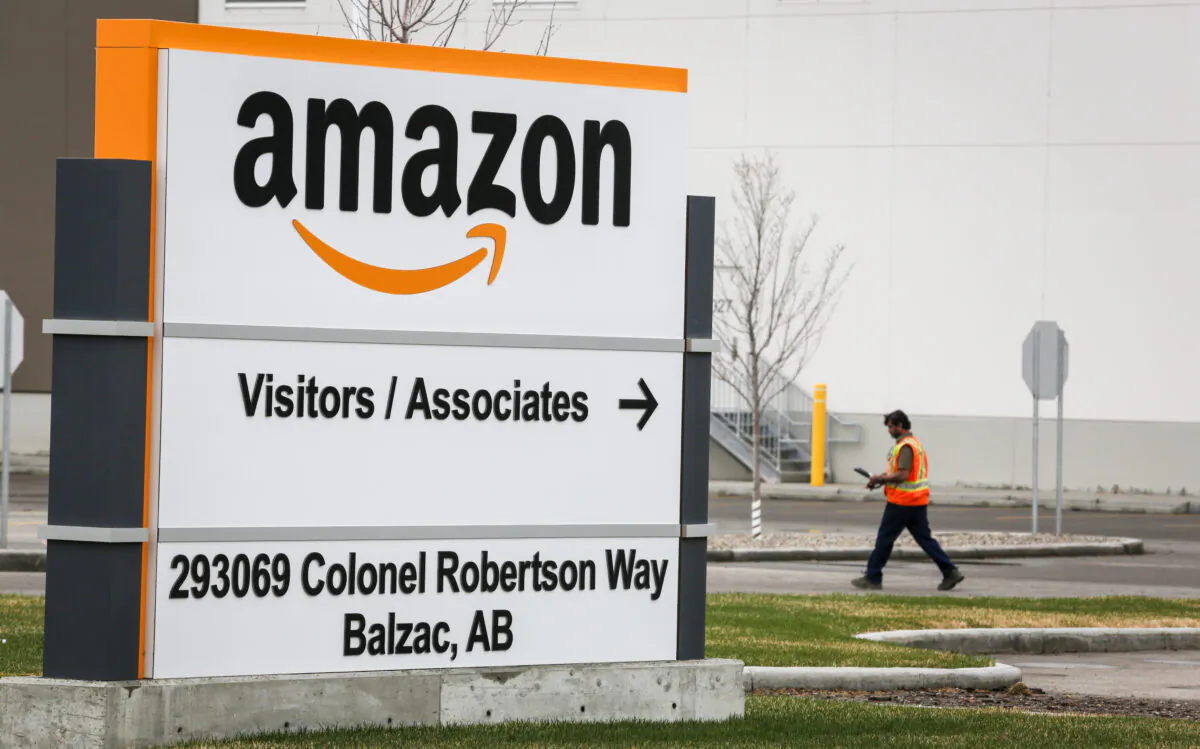 A worker walks past signage at an Amazon warehouse north of Calgary in Balzac, Alta. (Jeff McIntosh/The Canadian Press)