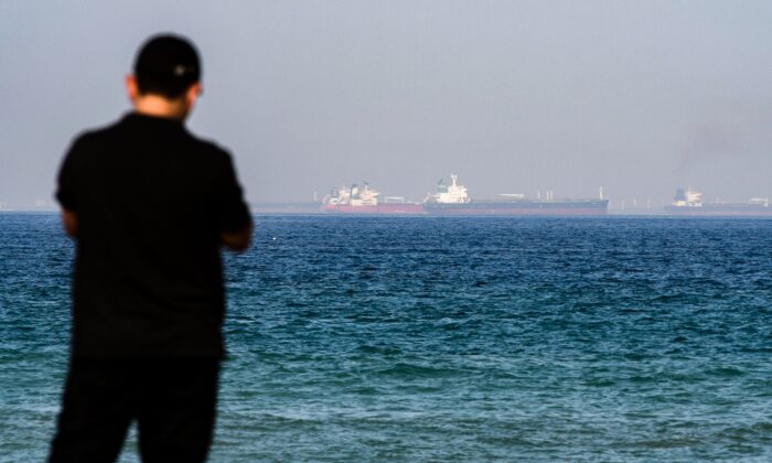 A man stands along a beach as tanker ships are seen in the waters of the Gulf of Oman off the coast of the eastern UAE emirate of Fujairah on June 15, 2019. (Giuseppe Cacace/AFP via Getty Images)