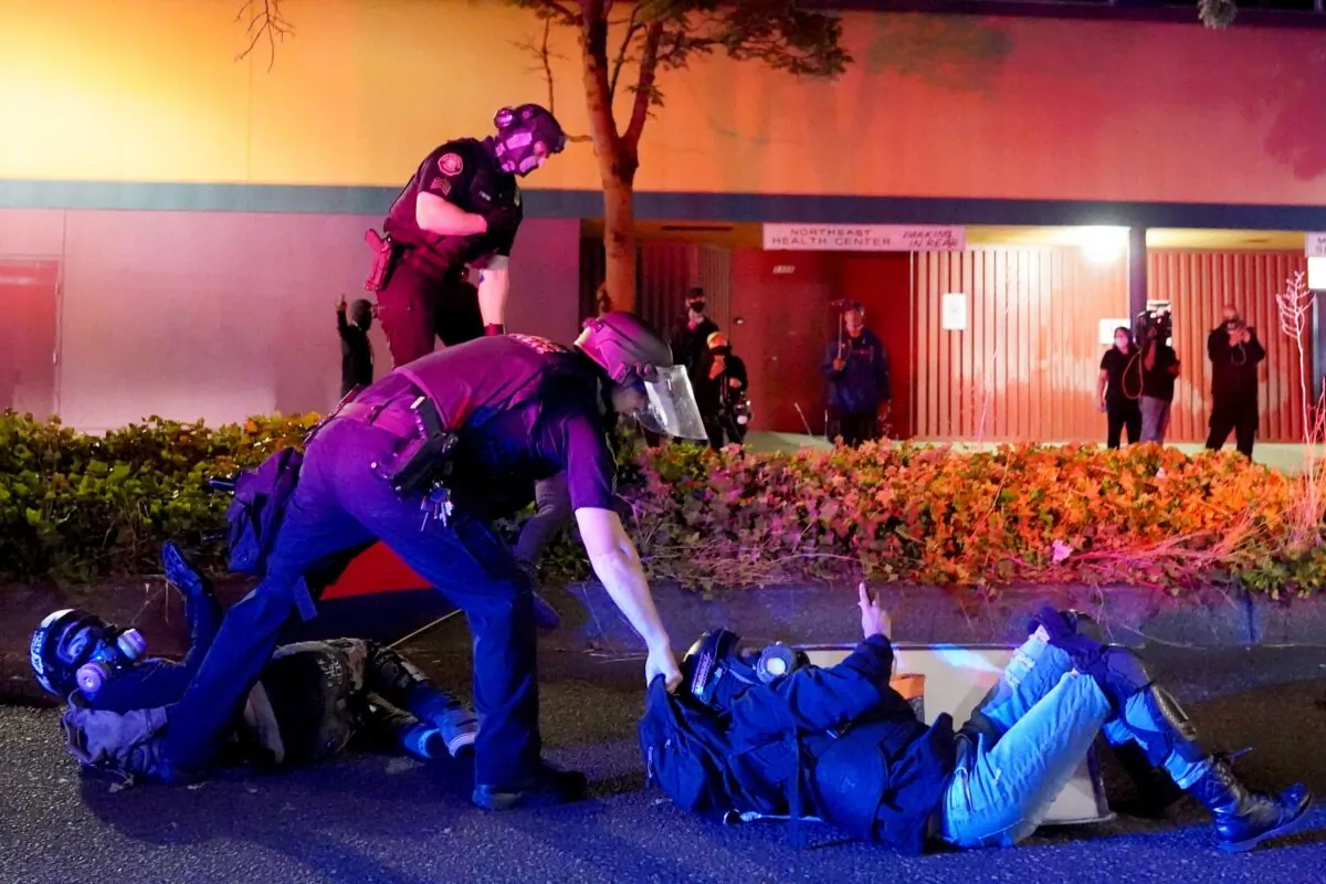 Portland police and Oregon State Patrol troopers work together to arrest two protesters in front of the Portland Police Bureau's North Precinct during continued rioting in Portland, Ore., on Aug. 11, 2020. (Nathan Howard/Getty Images)
