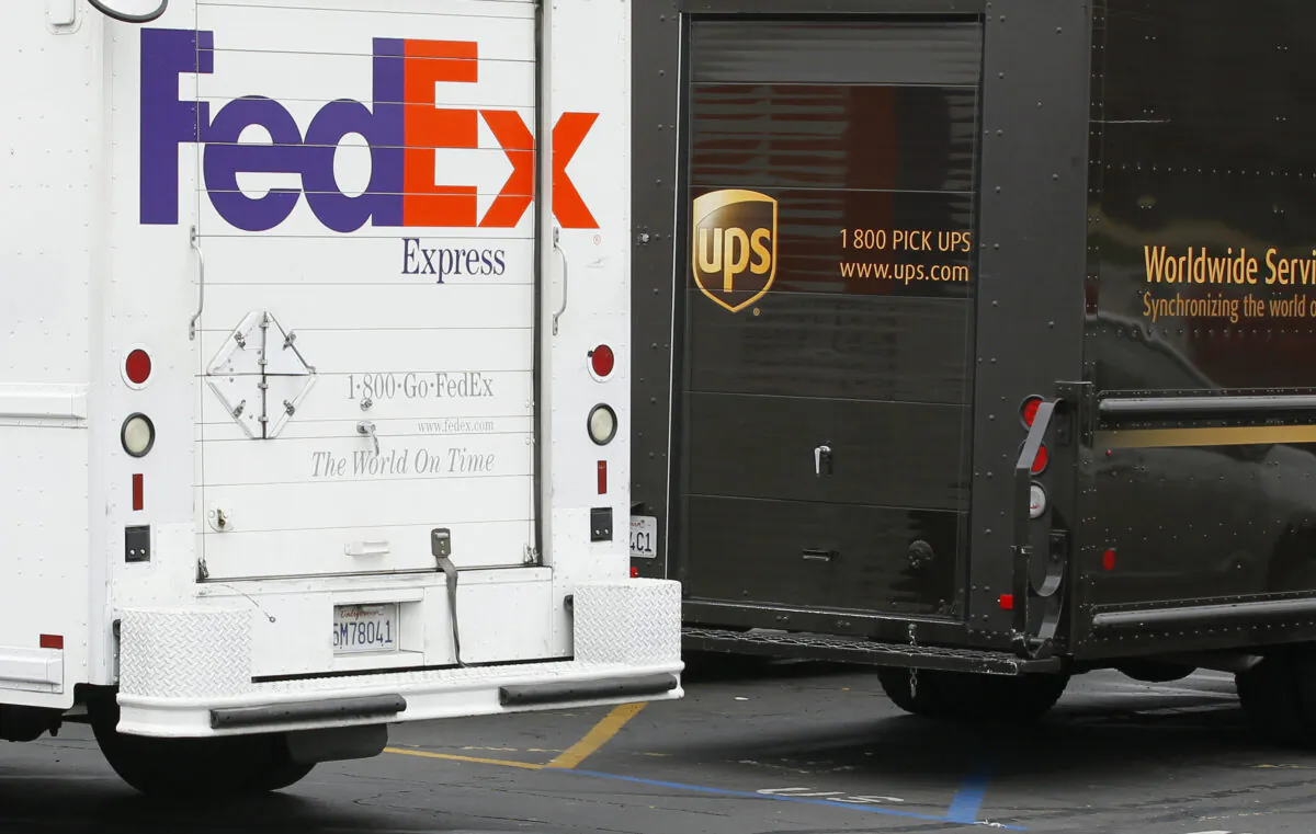 A FedEx truck is parked next to a UPS truck as both drivers make deliveries in San Diego, Calif., on Mar. 5, 2013. (Mike Blake/Reuters)