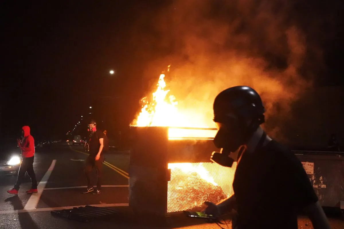 Rioters walk past a dumpster fire in Portland, Ore., on Aug. 14, 2020. (Nathan Howard/Getty Images)