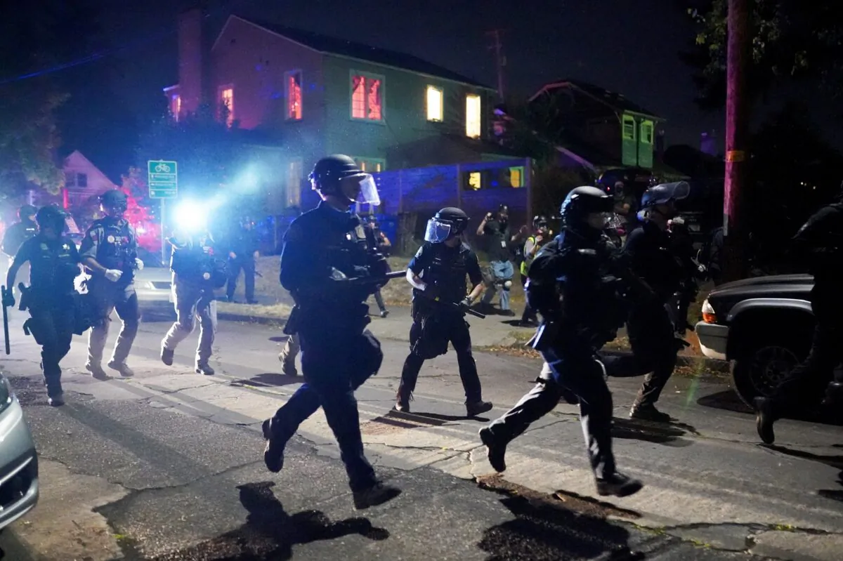 Police run through a residential neighborhood while dispersing a crowd of about 400 rioters in Portland, Ore., on Aug. 14, 2020. (Nathan Howard/Getty Images)