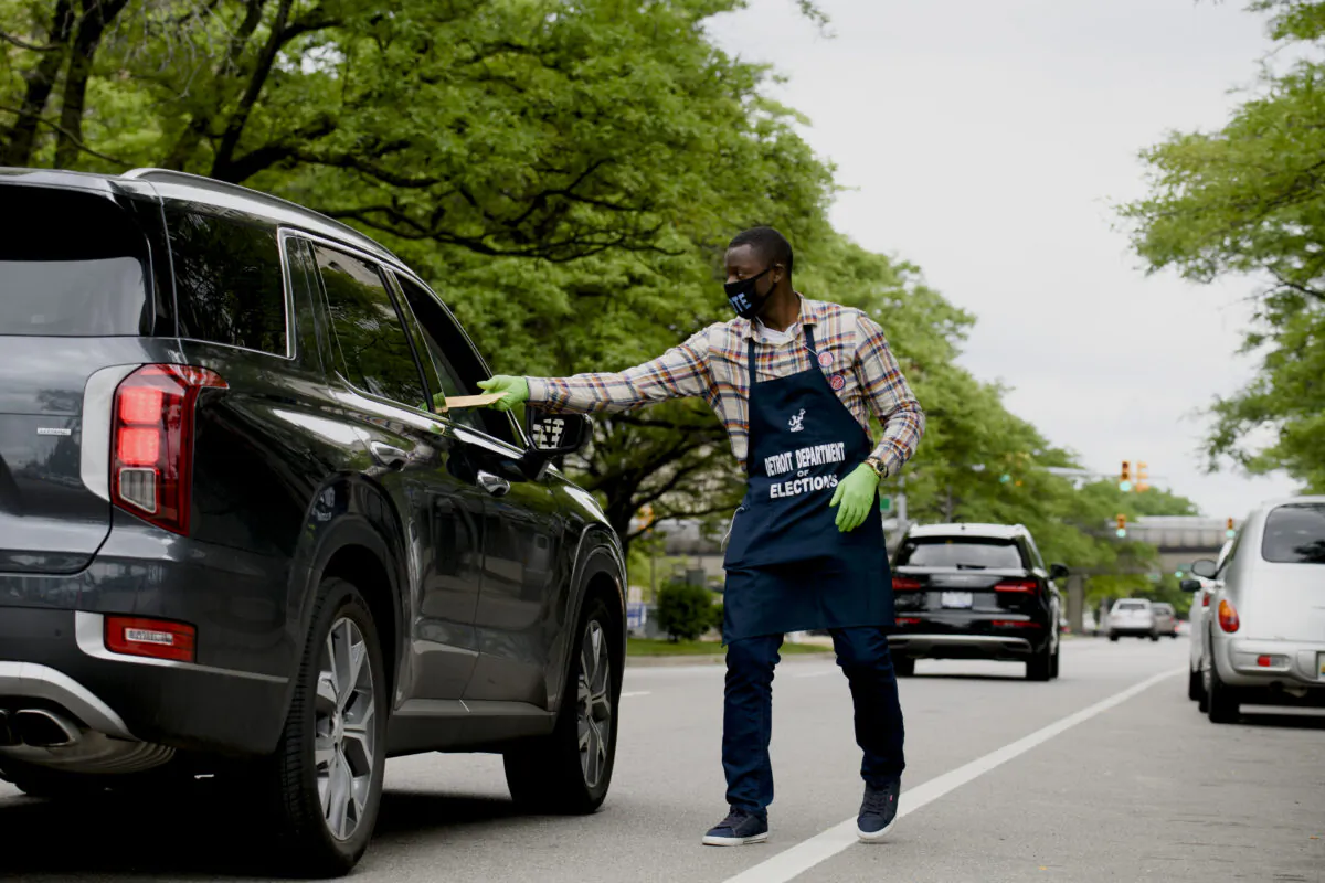 Election worker Demario Thurmond collects a sealed ballot curbside outside of the City of Detroit Department of Elections during the Michigan Primary Election in Detroit on Aug. 4, 2020. (Brittany Greeson/Getty Images)