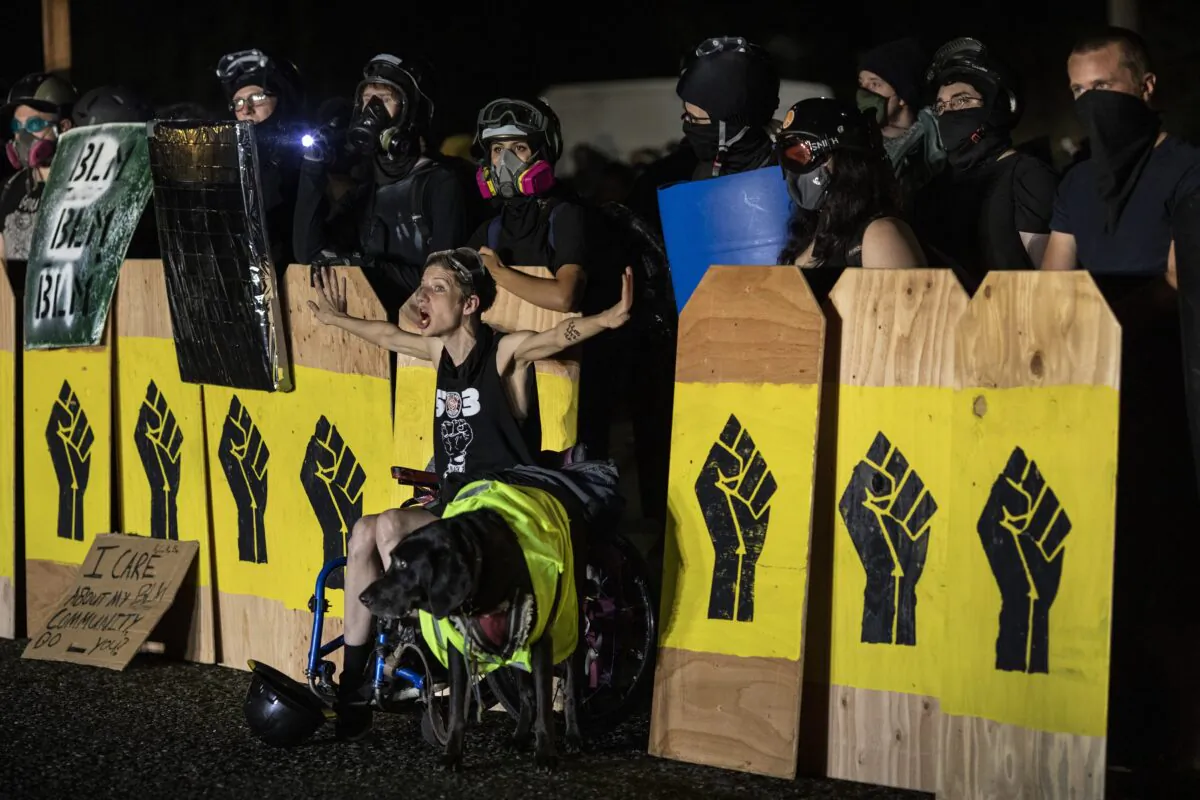A woman screams at police as demonstrators hold signs emblazoned with a Black Lives Matter symbol in Portland, Ore., on Aug. 15, 2020. (Paula Bronstein/Getty Images)
