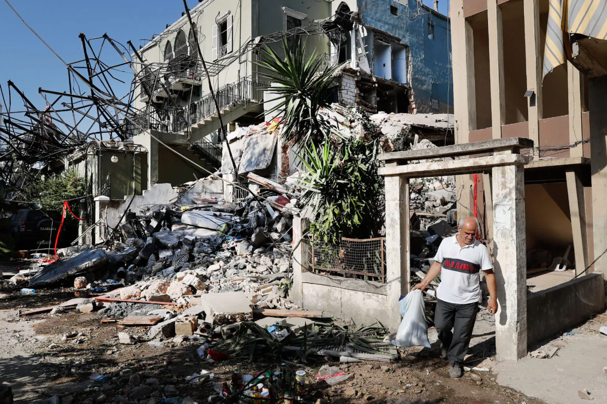 A Lebanese man carries his belongings as he leaves his destroyed house near the scene where an explosion hit on Tuesday the seaport of Beirut, Lebanon on Aug. 6, 2020. (AP Photo/Hussein Malla)