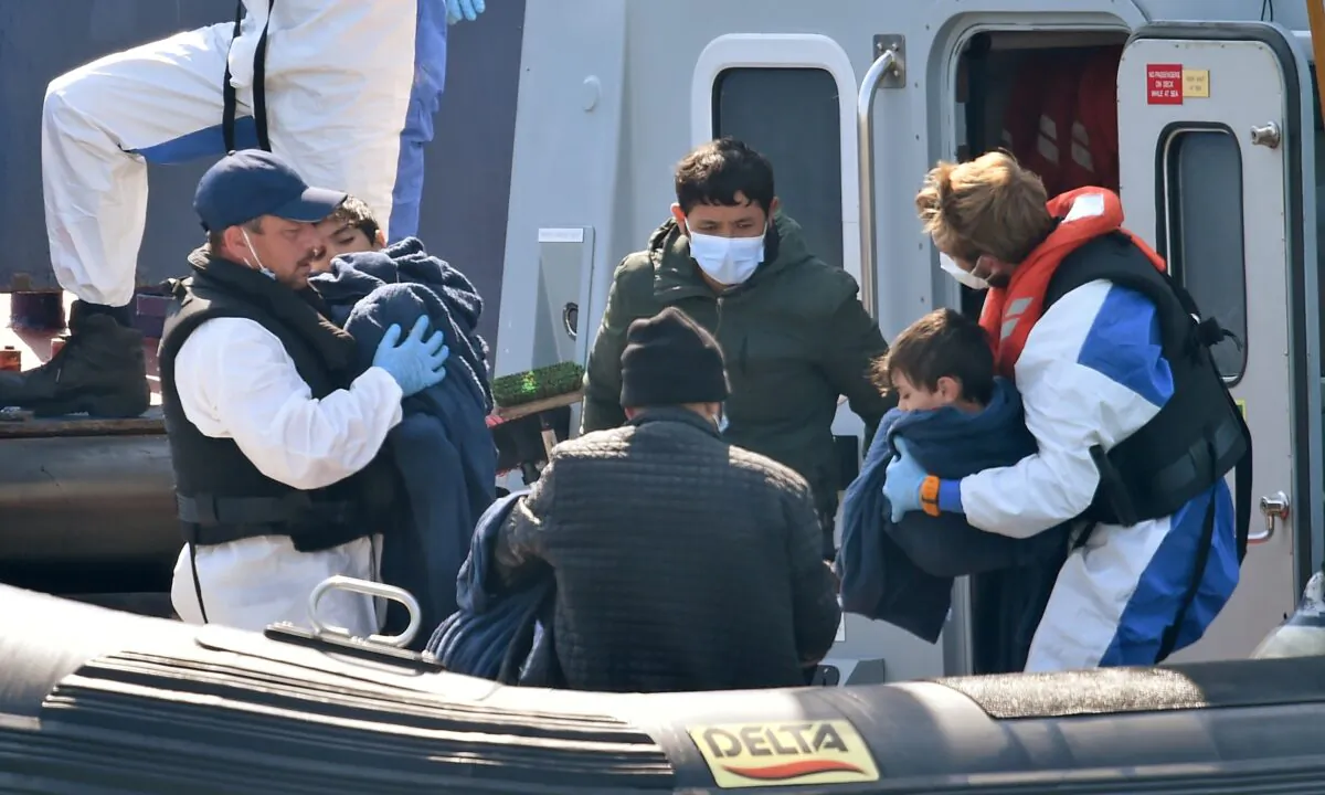 UK Border Force officers help migrants with children, believed to have been picked up from boats in the Channel, disembark from Coastal patrol vessel "HMC Hunter", in the port of Dover, on Aug. 9, 2020. (Glyn Kirk /AFP via Getty Images)