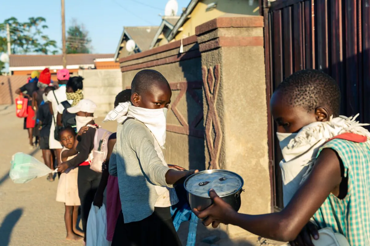 A queue of needy individuals line up for a free meal during the government-imposed CCP virus lockdown period in Chitungwiza, Zimbabwe, on May 5, 2020. (JEKESAI NJIKIZANA/AFP via Getty Images)