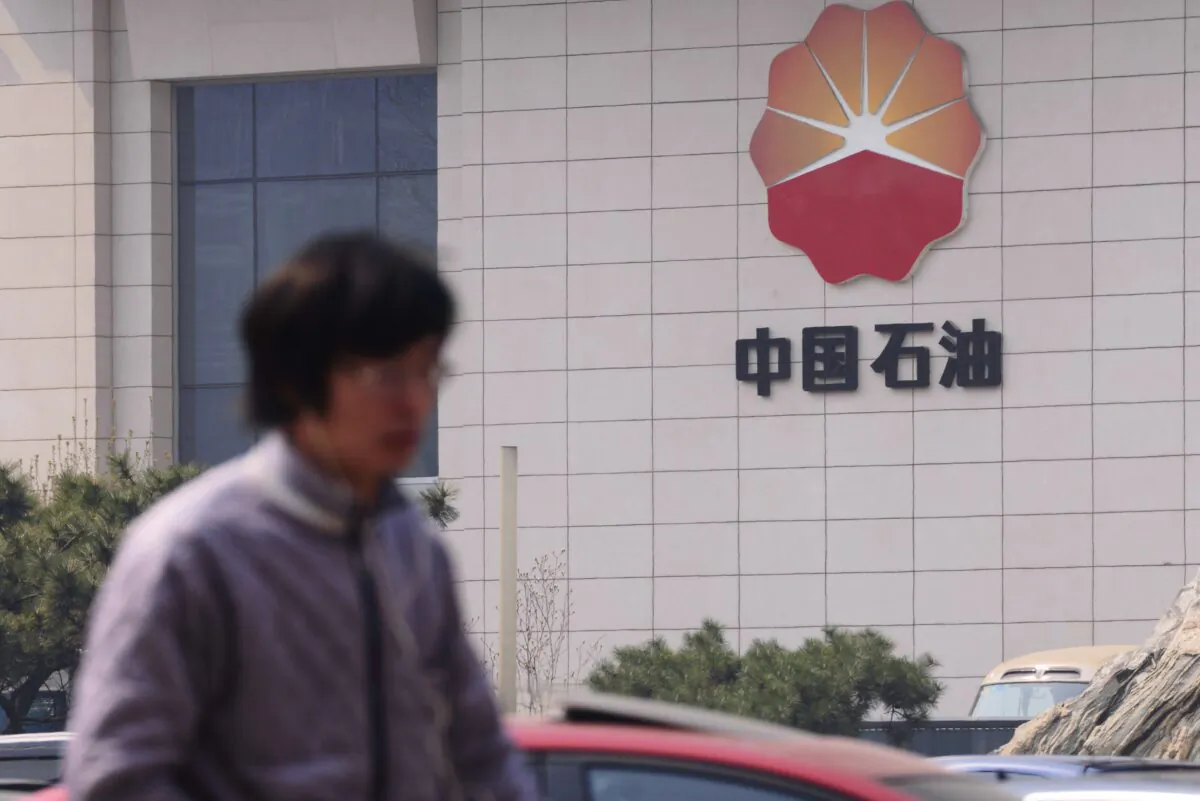 People walk by the headquarters of the China National Petroleum Corporation in Beijing on March 25, 2015.  (STR/AFP via Getty Images)