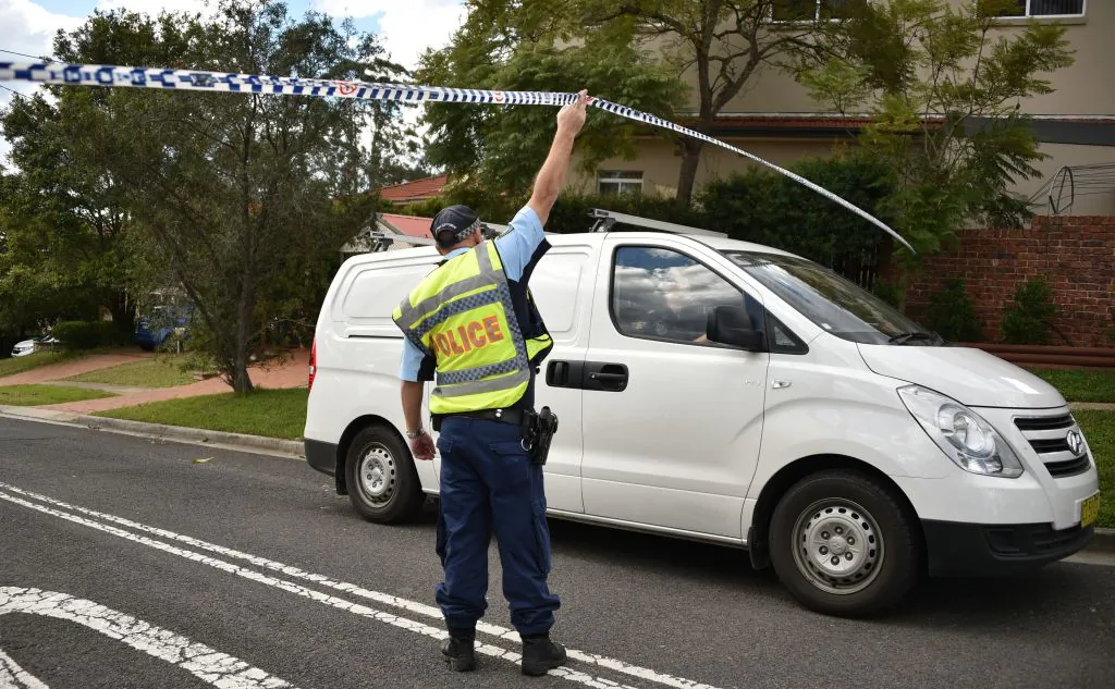 A policeman lets a van leave a street where a father shot dead his teenage son and daughter at their home in Sydney on July 6, 2018. (PETER PARKS/ Getty Images)