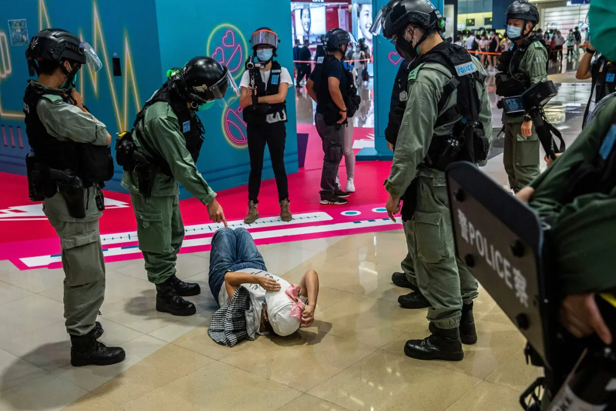 A riot police officer (2L) points at a woman lying down after being searched during a demonstration in a mall in Hong Kong on July 6, 2020, in response to Beijing's new national security law. (Isaac Lawrence/AFP via Getty Images)