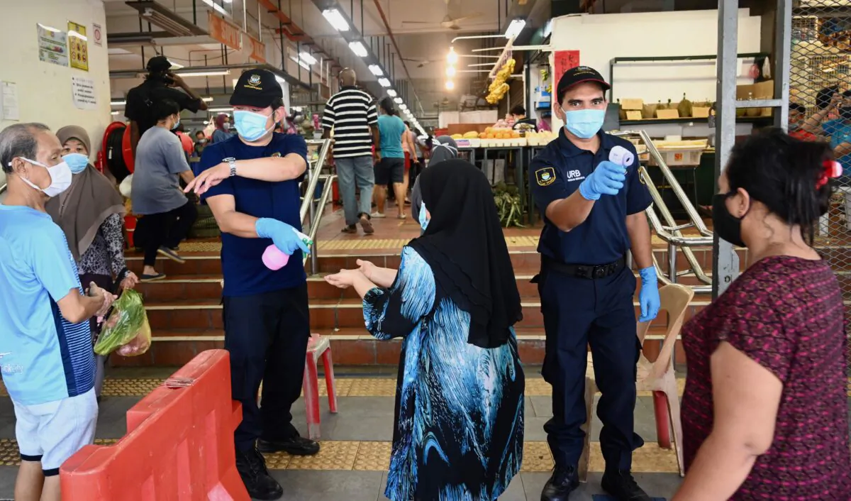 Security personnel check the temperatures of people entering a market, while enforcing social distancing, in Penang, Malaysia, on May 29, 2020. (Goh Chai Hin/AFP via Getty Images)