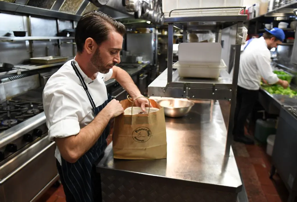 Chef packs a take-away meal in the kitchen of French restaurant France-Soir in Melbourne on May 8, 2020. (William West/AFP via Getty Images)