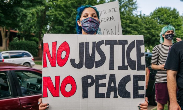 A woman stands with a sign that reads "No Justice No Peace" during a demonstration in St. Paul, Minn., on June 24, 2020. (Brandon Bell/Getty Images)