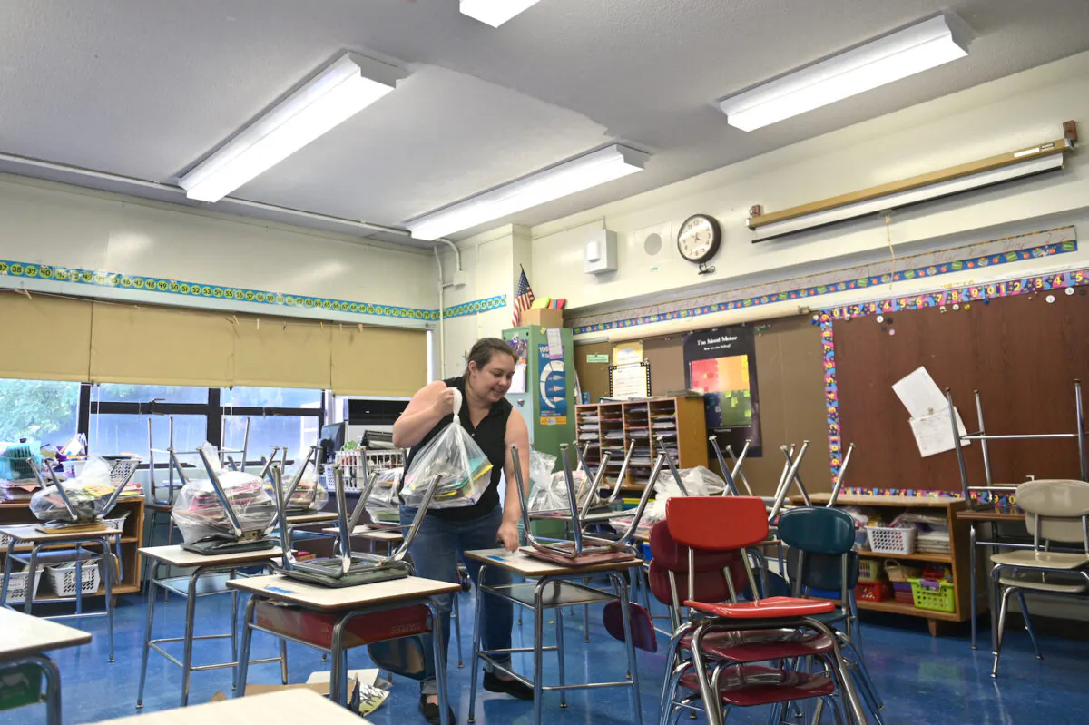 A teacher at Yung Wing Elementary School moves desks and chairs in her classroom to socially distance desks for the 2020-21 school year in New York City, N.Y., on Aug. 17, 2020. (Michael Loccisano/Getty Images)