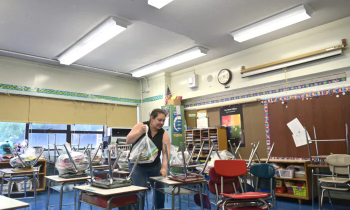 A teacher at Yung Wing Elementary School moves desks and chairs in her classroom to socially distance desks for the 2020-21 school year in New York City, N.Y., on Aug. 17, 2020. (Michael Loccisano/Getty Images)